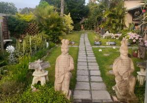 a garden with statues of people sitting on a path at Vincentia Odd Cottage ( self catering) in East London