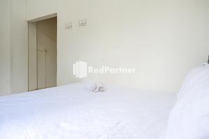 Una cama blanca con un par de zapatos. en Pringgondani Guest House At Pandanaran Hills Semarang en Semarang