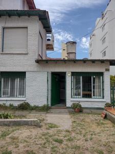 una vieja casa blanca con una puerta verde en Kuka 2, en Villa Gesell