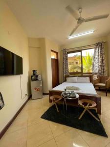 a bedroom with a bed and a tv and a table at SeaOne Nyali Mombasa Private Studio w/ pool in Mombasa