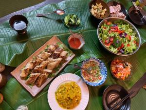 a table with a bunch of food and a salad at 猫のいる宿Happy Island Miyako-CatFriendlyGuesthouse in Miyako-jima