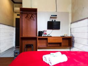 a room with a bed and a desk with a television at Hotel 41 Maribaya in Tegal
