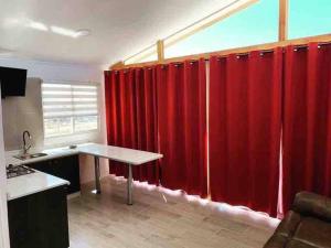 eine Küche mit roten Vorhängen und einem Tisch im Zimmer in der Unterkunft Cabaña en Tongoy in Tongoy