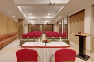 una sala de conferencias con sillas rojas, una mesa y un podio en Click Hotel Caliph, Mumbai en Bombay