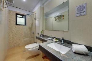 a bathroom with a sink and a toilet and a mirror at Click Hotel Caliph, Mumbai in Mumbai