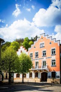 un gran edificio naranja y blanco con árboles delante en Gasthaus Schwan, en Riedenburg