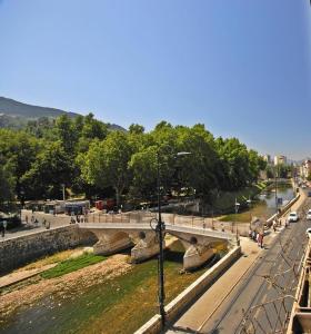 uma ponte sobre um rio com pessoas andando na rua em Studio Park em Sarajevo