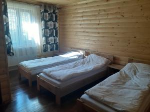 3 camas en una habitación con paredes de madera y ventana en Біла хата, en Iltsi
