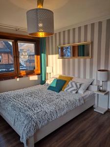 een slaapkamer met een bed, een lamp en ramen bij Apartament Stanisława in Zakopane