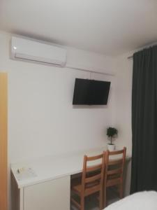 a room with a desk and a television on a wall at Sobe Šušanj in Karlobag