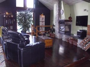 uma sala de estar com cadeiras de couro preto e uma lareira em Les Chanterelles em Jalhay