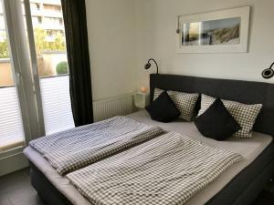 a bed with black and white sheets and pillows at Leuchtturm Leuchtturm 7 - Dachterrasse mit Meerblick in Großenbrode