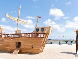 a wooden boat on the beach with a pier in the background at Leuchtturm Leuchtturm 7 - Dachterrasse mit Meerblick in Großenbrode