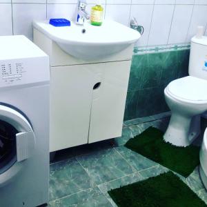 a bathroom with a sink and a toilet and a washing machine at Квартира 5-9 in Aktau