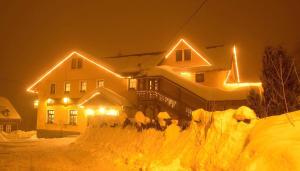 布布拉瓦的住宿－斯維克餐廳酒店，雪覆盖的房屋,晚上有灯
