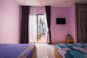 1 dormitorio con paredes de color púrpura y ventana con TV en Nemo Homestay, en Hue