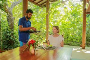 Ein Mann und eine Frau sitzen an einem Tisch mit Essen in der Unterkunft Nature Lanka Ayurveda Resort - All Meals and Ayurveda Treatments with Yoga in Tangalle