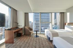 ソウルにあるStanford Hotel Myeongdongのベッドと大きな窓が備わるホテルルームです。