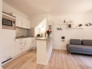 una cocina con armarios blancos y un sofá en una habitación en Feriendorf Rugana - Komfort Appartement mit 1 Schlafzimmer und Terrasse B16, en Dranske