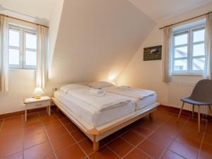 1 Schlafzimmer mit einem Bett, 2 Fenstern und einem Stuhl in der Unterkunft Feriendorf Rugana - Klassik Appartement mit 2 Schlafzimmern und Terrasse D01 in Dranske + 3 Fotos