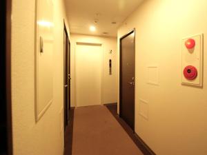 Web Hotel Tokyo Asakusabashi في طوكيو: ممر له بابين و علامة توقف حمراء
