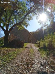 un chemin de terre à côté d'une grange avec un arbre dans l'établissement Appartement de charme dans une maison isolée, à Présilly