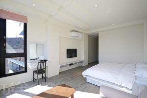 a bedroom with a bed and a desk and a tv at Riyuewan Homestay in Yuchi