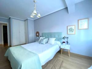 a blue bedroom with a white bed and a table at Housingleón San Isidoro in León