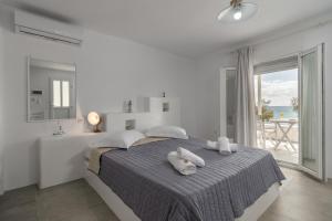 a white bedroom with a bed with towels on it at Aqua Bay Agia Kyriaki in Agia Kiriaki Beach