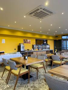 a restaurant with wooden tables and chairs and yellow walls at Roy Otel in Akçay
