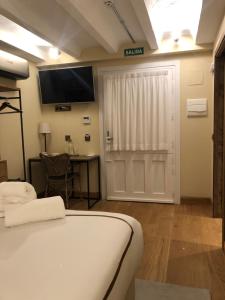 a room with a bed and a desk and a television at Hotel Boutique Casa del Comendador in Navalcarnero
