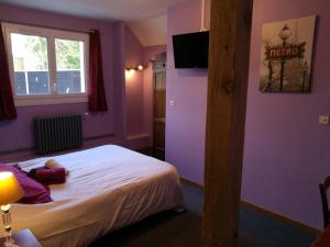 Habitación de hotel con paredes moradas y cama en Auberge Normande en Valframbert