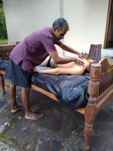 a man getting a massage from a woman on a bed at The Pepper Cottage in Gomagoda
