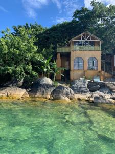 a house on the shore of a river with rocks at Mayoka Village Beach Lodge in Nkhata Bay