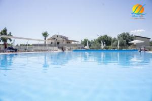 a large swimming pool with blue water at Village Due Elle in Marina di Schiavonea