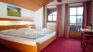 a bedroom with a bed and a desk and windows at Pension Traube in Uderns