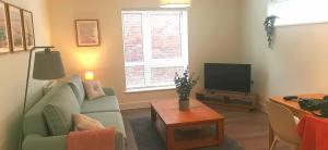 een woonkamer met een bank en een tv bij Apartment one Estuary Reach in Exmouth