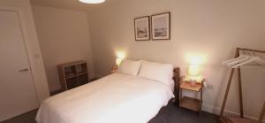 een slaapkamer met een wit bed en 2 lampen bij Apartment one Estuary Reach in Exmouth