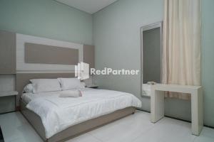 a bedroom with a white bed and a white table at Yayah Rooms Bogor Syariah Mitra RedDoorz in Bogor
