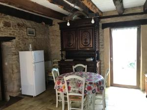 a kitchen with a table with chairs and a refrigerator at Gîte Le Meynet in Saint-Cyprien