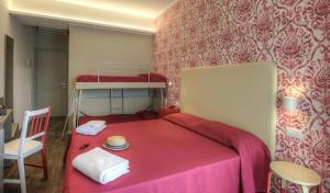 Hotel 2000 في ريميني: غرفة نوم مع سرير احمر مع كرسي وسرير بطابقين