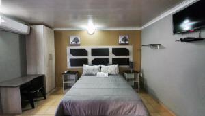 a bedroom with a large bed and a desk at Genesis Self Catering Apartments in Bloemfontein