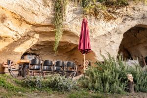 uma mesa com cadeiras e um guarda-sol numa caverna em B&B Bacchus Grotto with only 1 suite 45m2 plunge pool privé em Cairanne