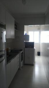 a kitchen with white cabinets and a white refrigerator at Frente pro mar apartamento completo in Praia Grande