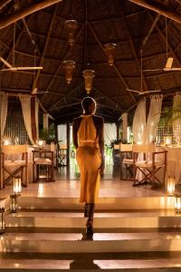 a woman in a yellow dress walking down the stairs of a restaurant at Lion in the Sun Billionaire Retreat Malindi in Malindi