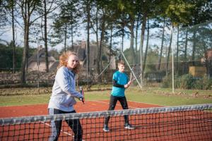 due giovani che giocano a tennis su un campo da tennis di campushus a Sankt Peter-Ording