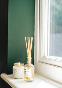 two candles and bamboo sticks in a jar on a window sill at Tranquil Little Hide-Away in Oxford with Private Garden in Oxford