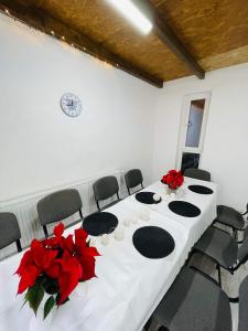 einen Konferenzraum mit einem weißen Tisch und roten Blumen in der Unterkunft Casa De Sub Deal in Densuş