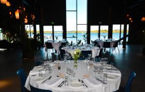 um grupo de mesas com panos de mesa brancos e copos em Kjerringøy Bryggehotell em Bodø