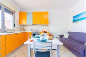 a kitchen with orange cabinets and a table and a purple couch at Piazza del Sole Apartment in San Salvo